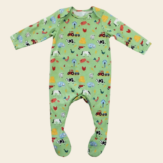 A green long-sleeved footed sleepsuit for babies with a farmyard animal print including cows, chickens, and tractors.