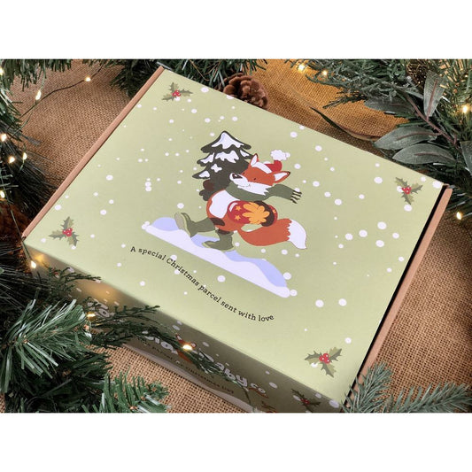 A Christmas themed gift box with illustrations of a fox and a robin on the lid, presented under a Christmas tree.
