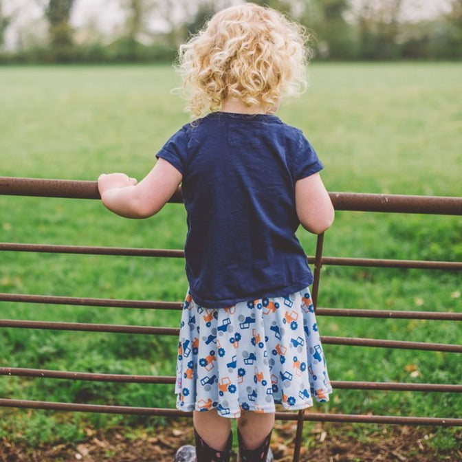 little girl wearing pastel blue tractor skirt by Toucan Blue | Cotswold Baby Co